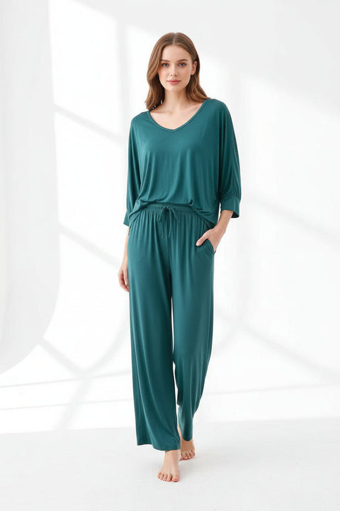 A green V-neck T-shirt and matching pajama nightsuit hanging on a wooden hanger, with the T-shirt displaying a round neckline and the nightsuit featuring a flowing paisley pattern.