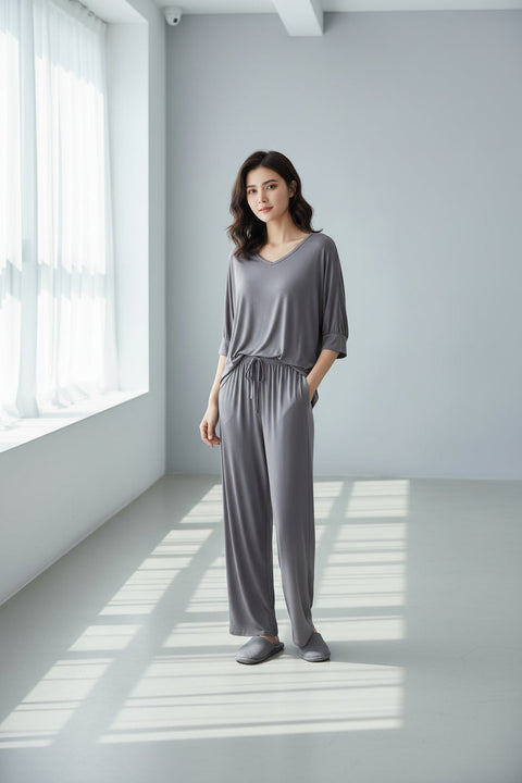 A plain grey V-neck pajama suit with full sleeves, displayed on a wooden hanger and a copper wire hanger below it.