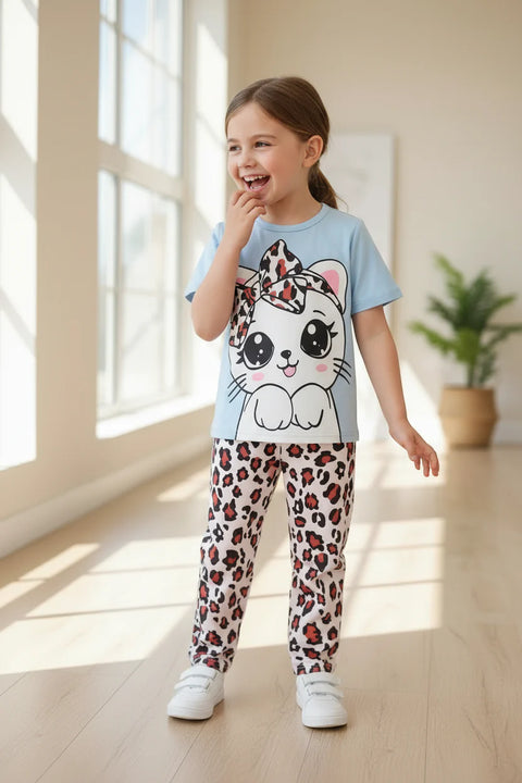 A kids' pajama set with a sky blue top featuring a cute kitty face with half sleeves and cheetah print pants. The set is displayed with white sneakers and a decorative room setting.