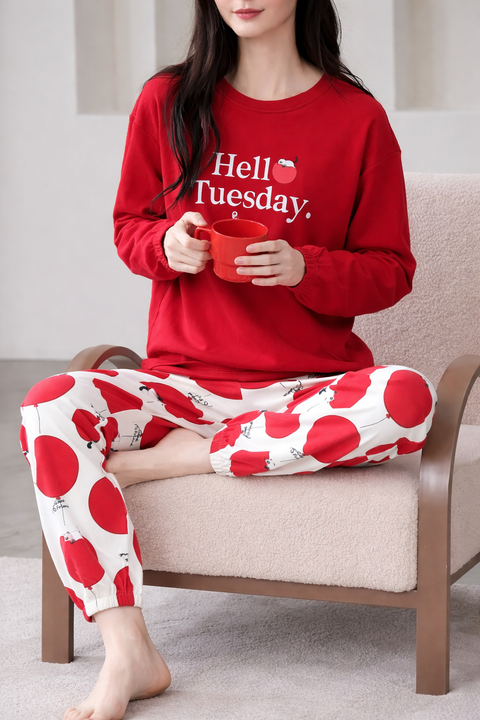 Person wearing a red pajama set with a humorous message, sitting on a chair.
