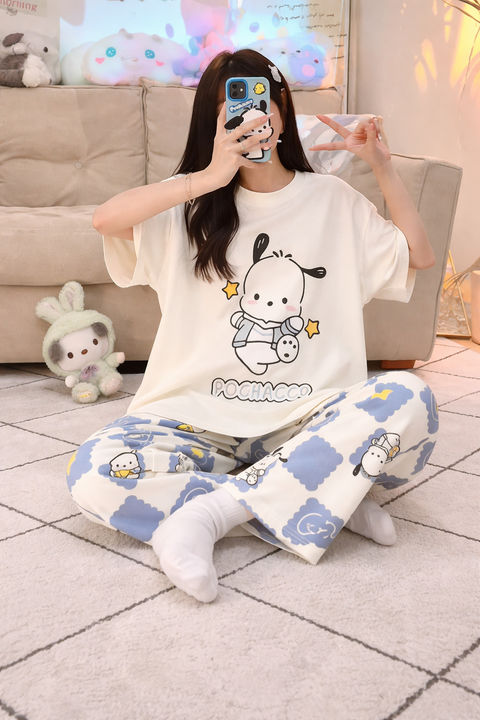 Person wearing a white t-shirt with a cartoon design and blue pajama pants with animal prints, sitting on the floor.
