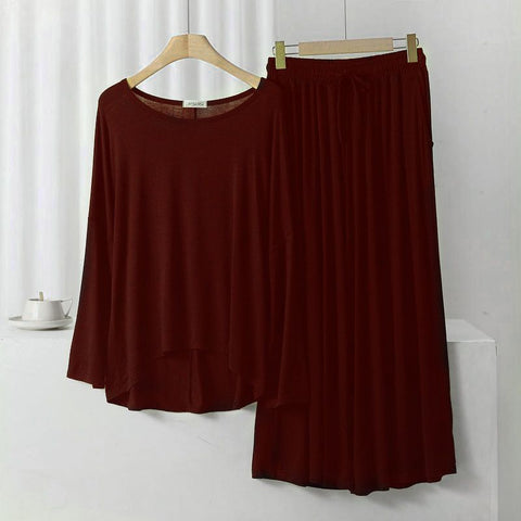 A maroon loose sleeves T-shirt and palazzo trouser suit hanging on wooden hangers against a white background.