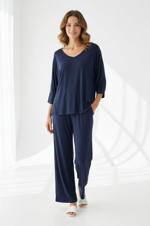 A navy blue V-neck top with palazzo style pajama bottoms, displayed on a wooden hanger.