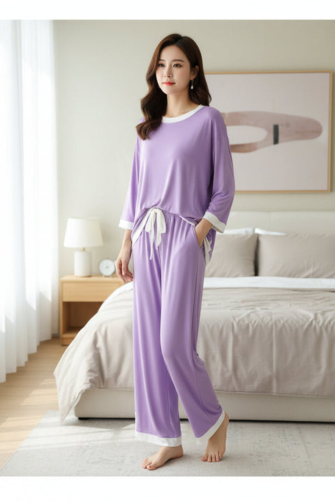 A purple pajama night suit with a round neck and white flapper design, displayed on a hanger in a store.